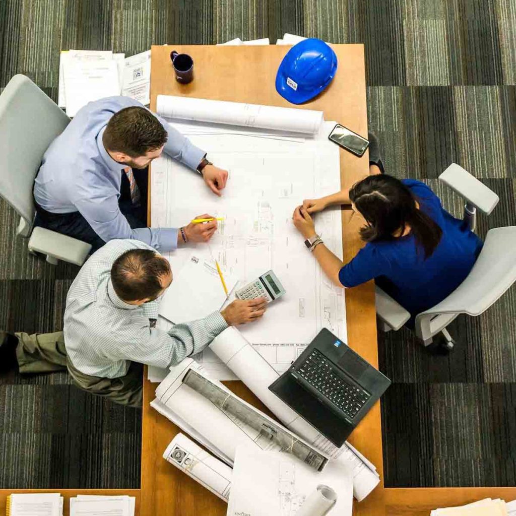 3 architects working a table with blueprint and other tools