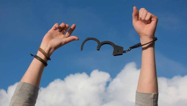 Two arms held high with handcuffs attached to one wrist
